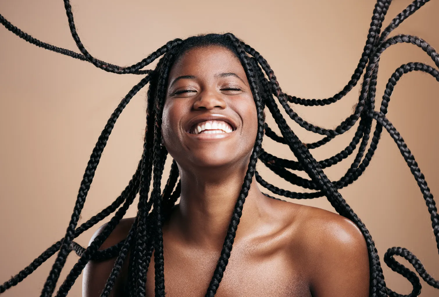 A smiling and happy african woman with bouncing hair braids.