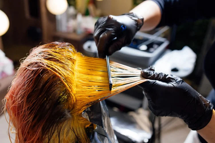 A hairdresser carefully putting the the dye chemical on the customer's hair.