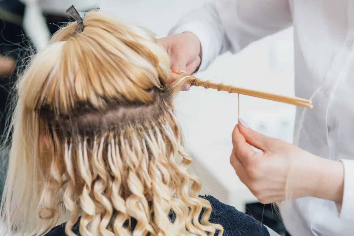 Beauty salon hairdresser separating each section of hair to put the extension hair on the customer.