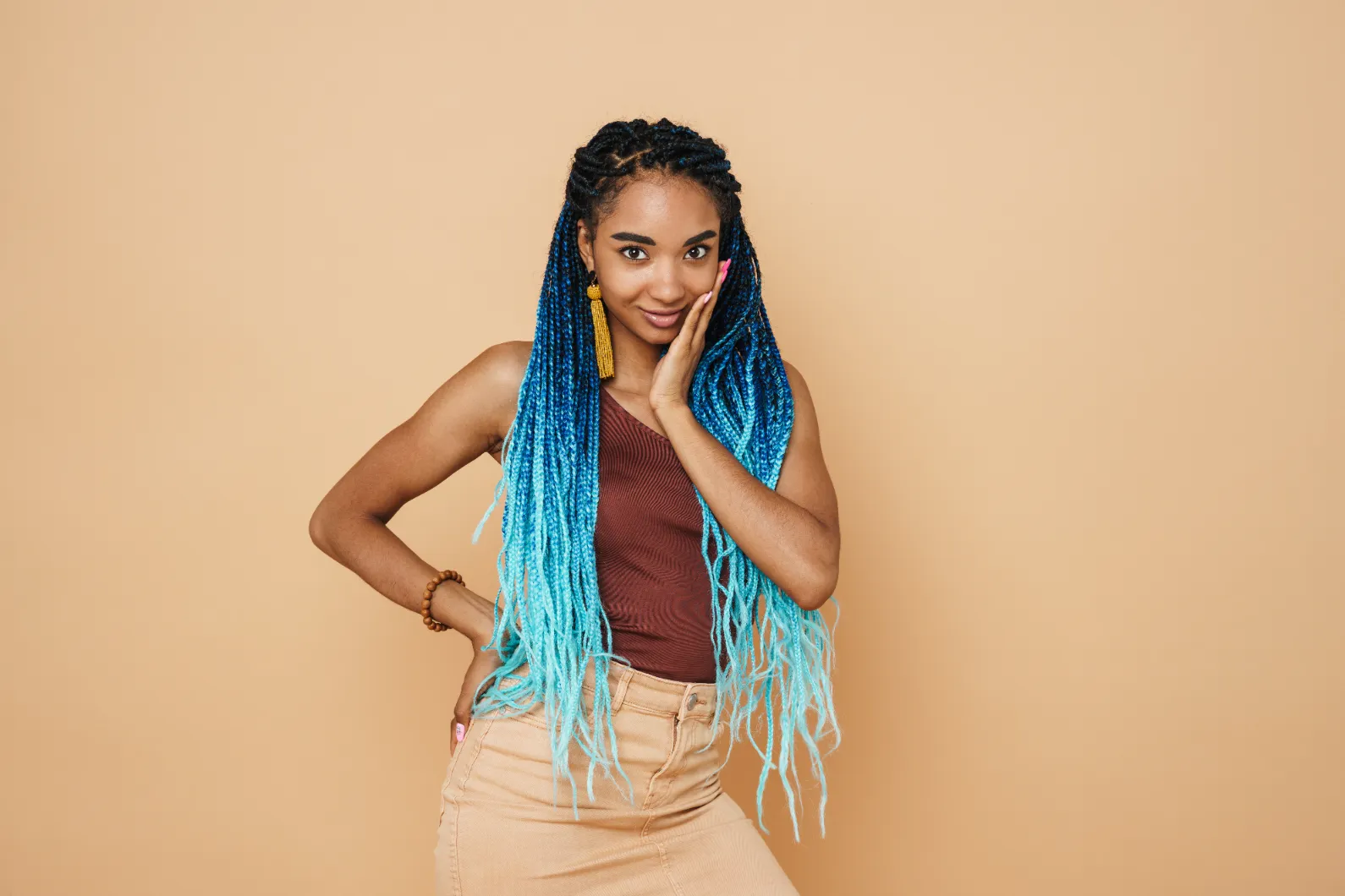 A smiling young black woman with blue ombre braids posing.